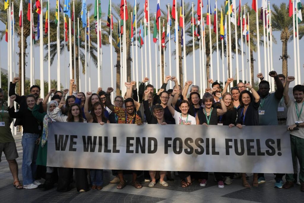 Members of Greenpeace gather for a photo around a sign that reads 'We will end fossil fuels!' (AP Photo/Rafiq Maqbool)